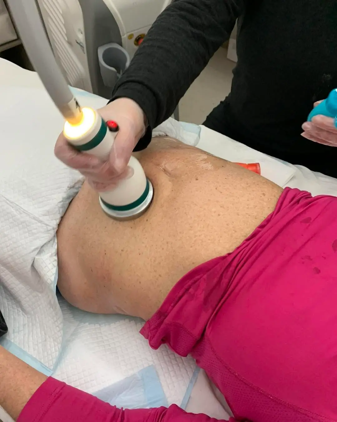 Provider positioning an Emsculpt Neo applicator on a reclining client's abdomen during a body sculpting session